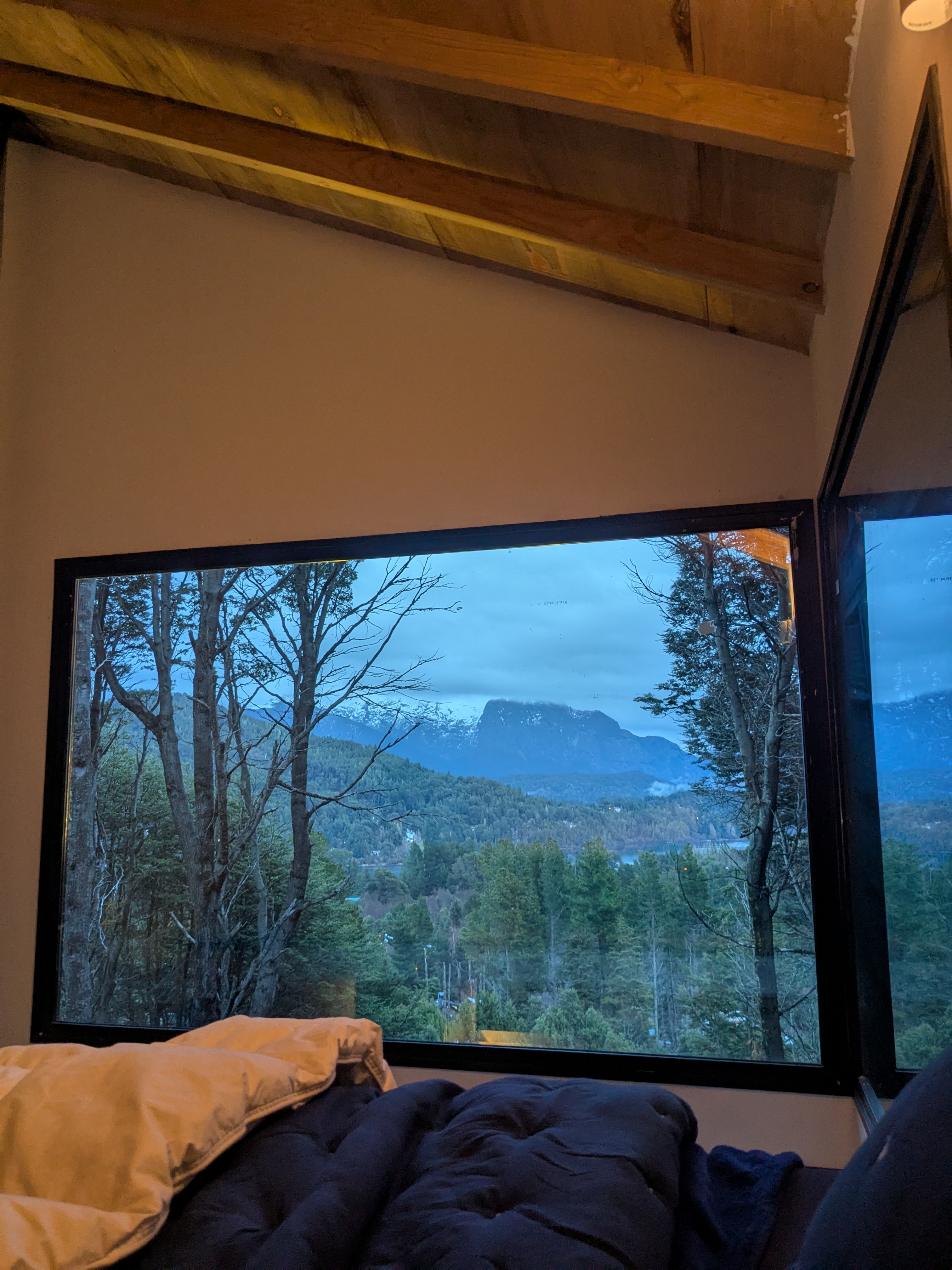 Bedroom — king bed, exposed beams, Cerro López at dusk